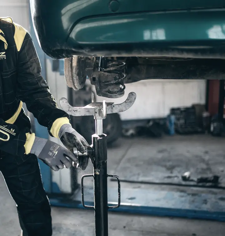 Mecánico revisando la suspensión de un auto en el elevador (foto ilustrativa)